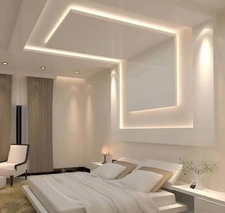 Slaapkamer met een verlaagd plafond, een lichtkoof rondom en een verlichte wand achter het bed